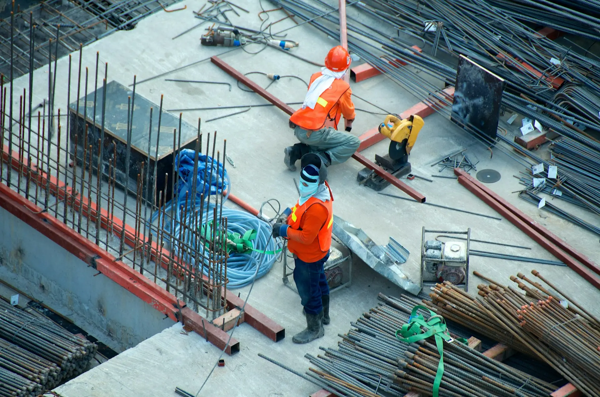 Construction workers in hard hats tying rebar on a jobsite, seen from above
